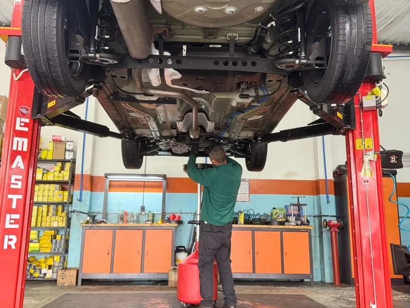 Mecânico trabalhando embaixo do carro na suspensão
